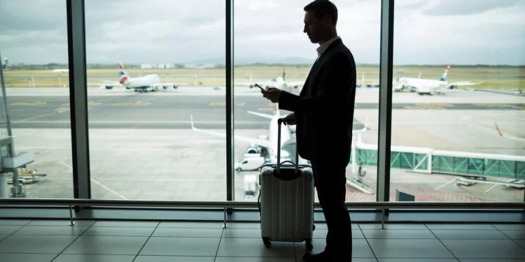 businessman-with-luggage-using-mobile-phone_107420-95902