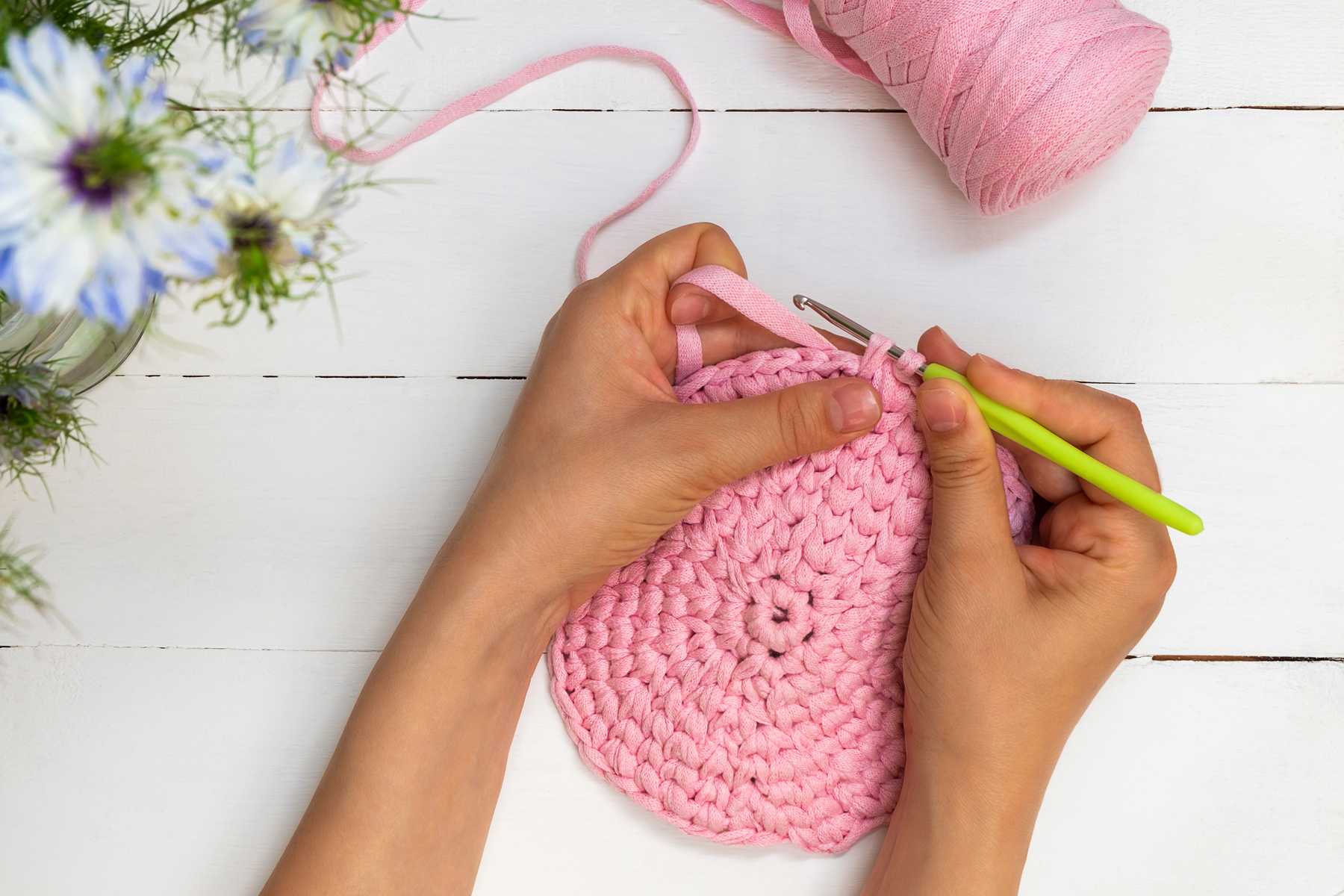 Directly above view of woman hands holding crochet hook and crocheting with ribbon yarn